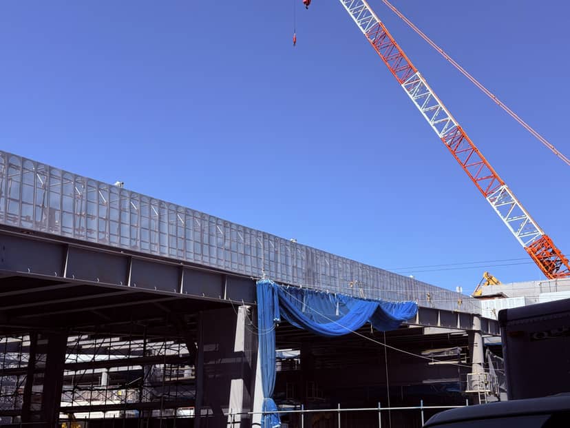 鉄骨の建方が進む現場と、青空に伸びるクレーンのブーム