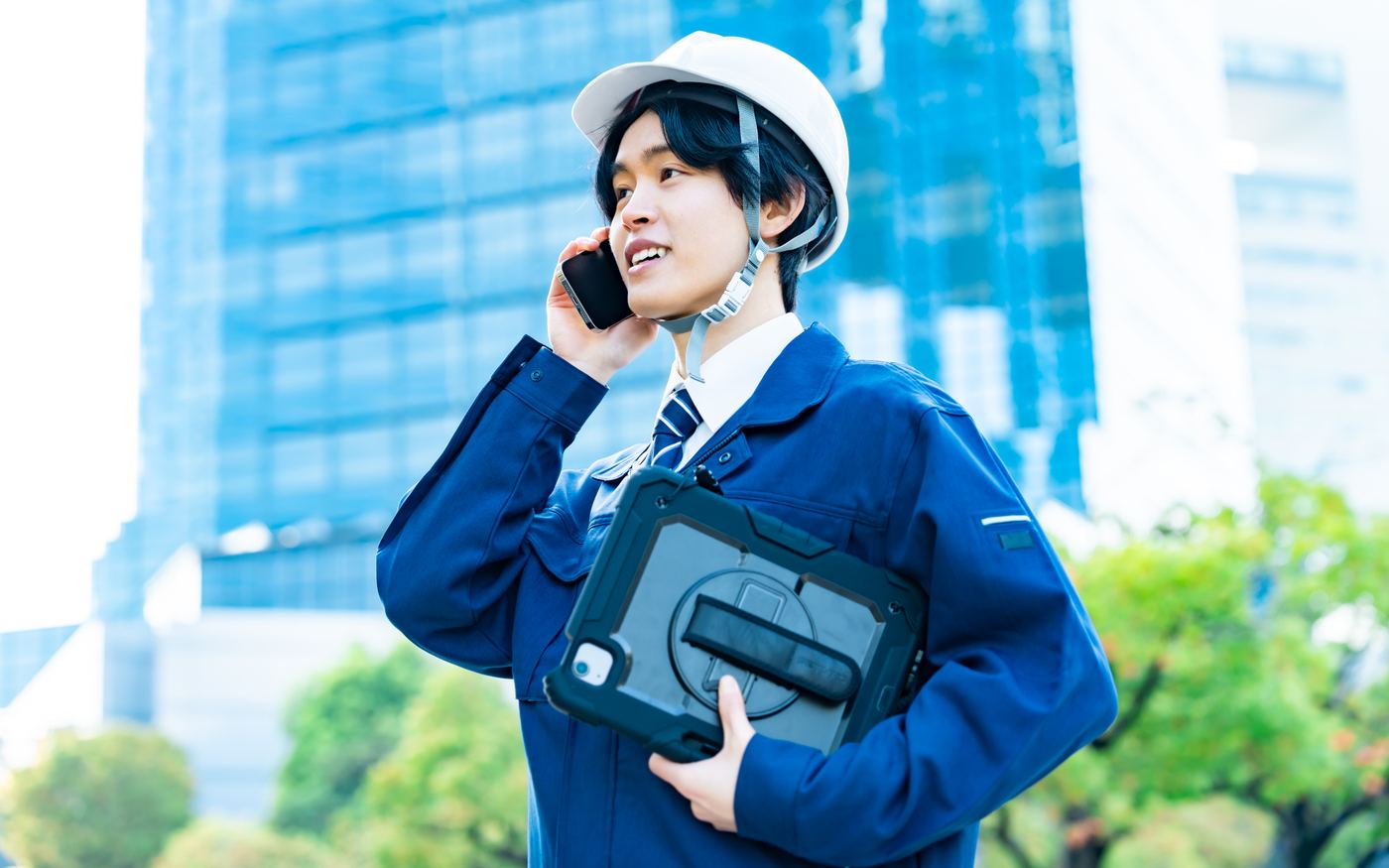 現場でヘルメットをかぶったままスマホに出る監督の写真（素材）