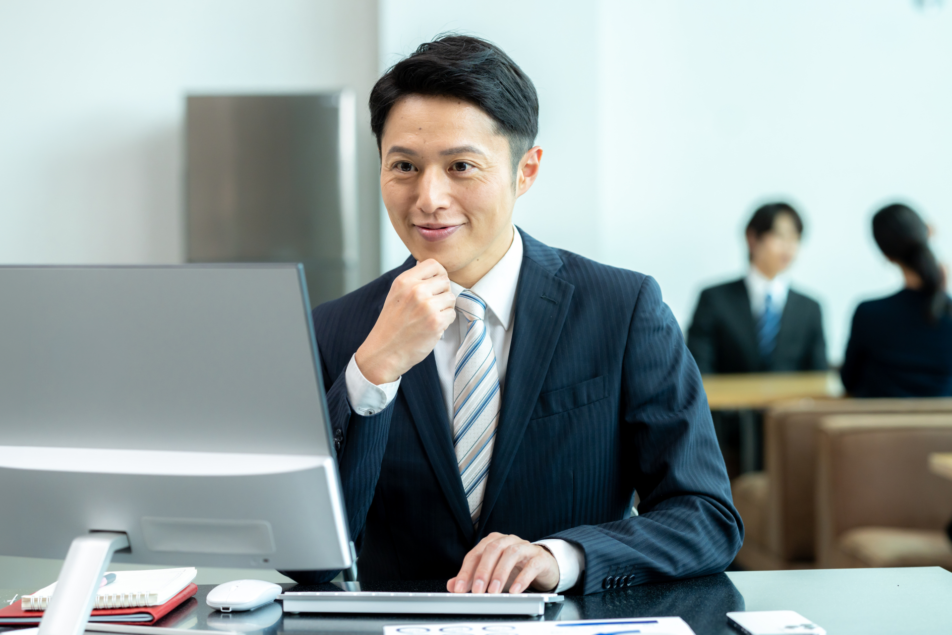 机でパソコンに向かい、考えている経営者