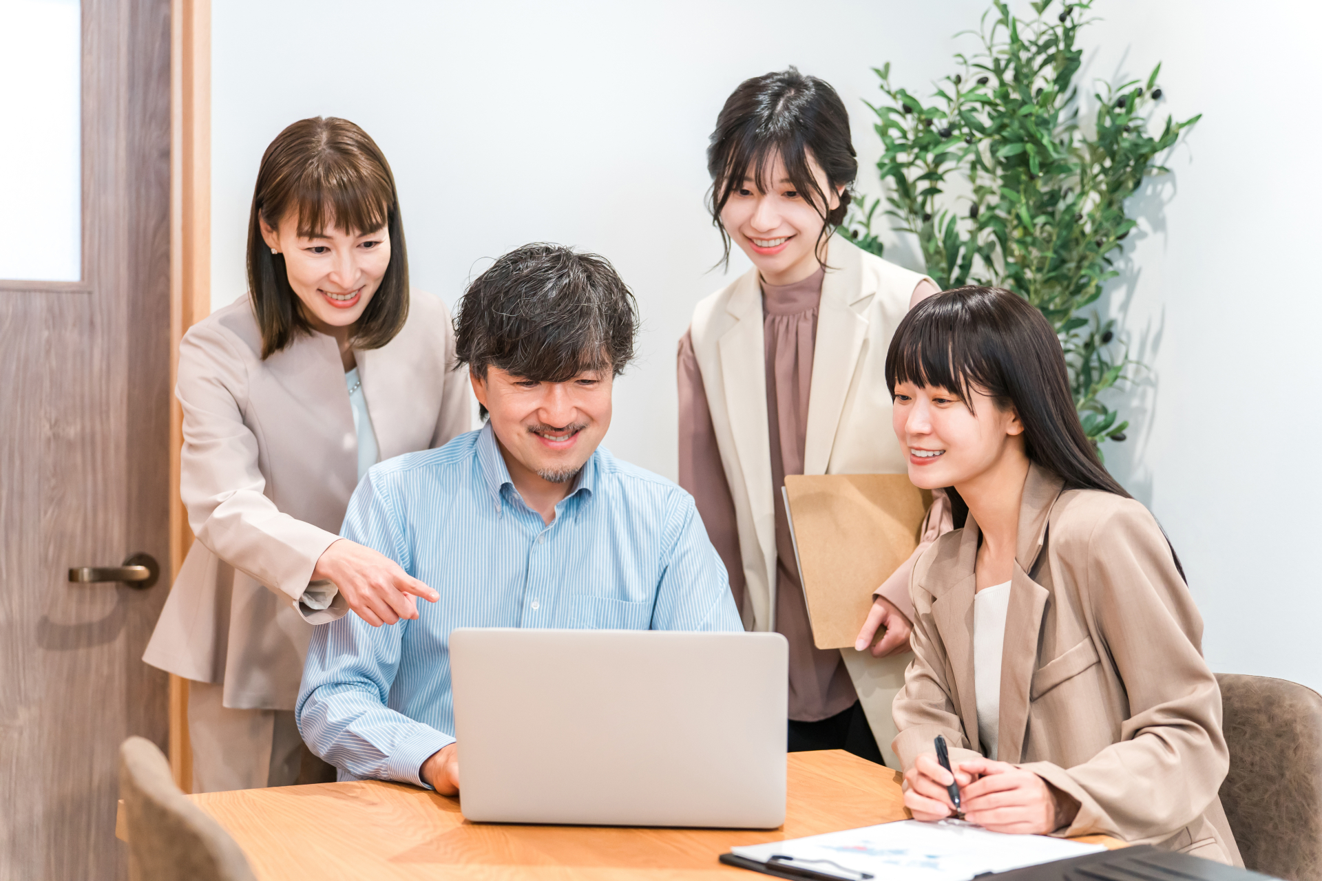事務所でノートパソコンの画面を囲んで相談している4名