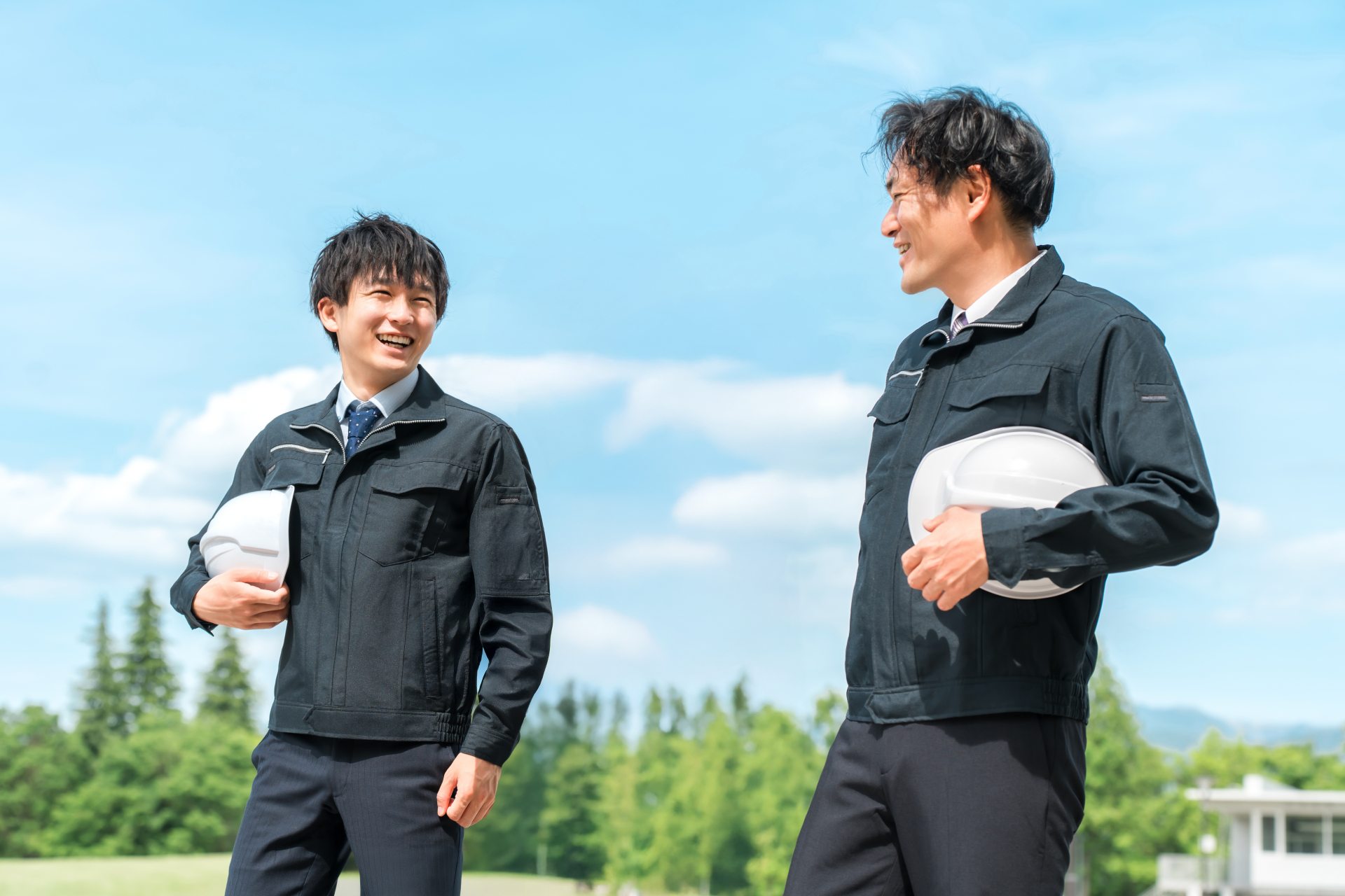 ヘルメットを抱えて話しながら歩く建設会社の社員2名